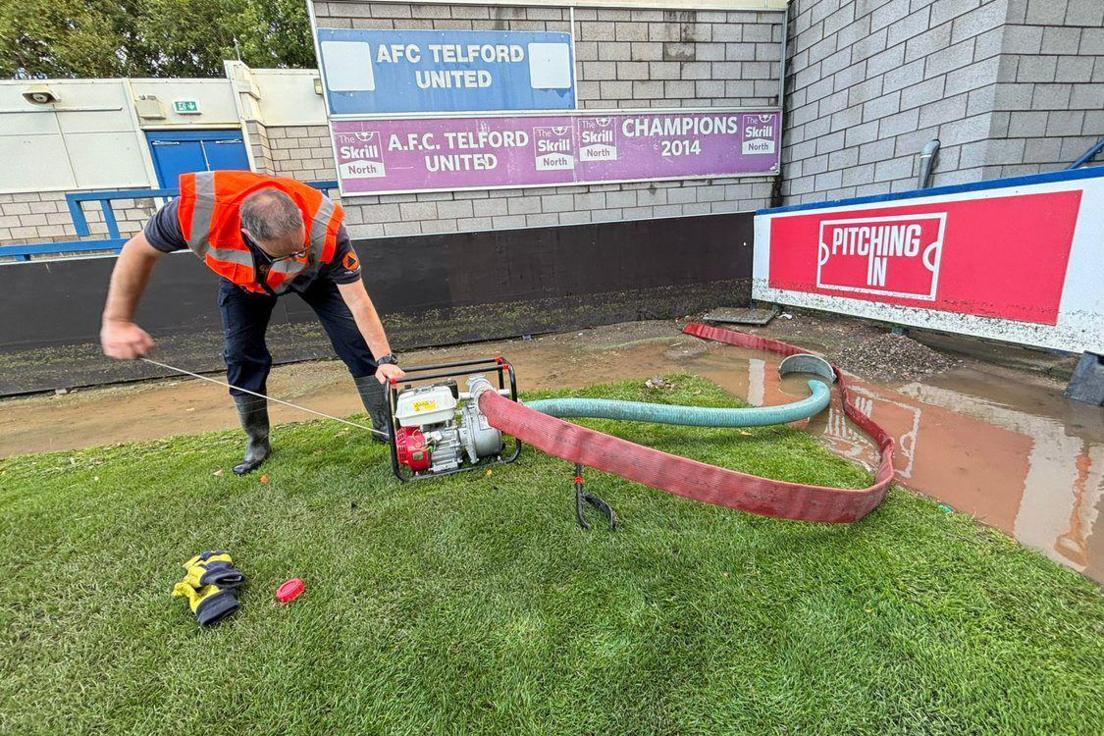 A man is using a pump to remove flood water from the football ground