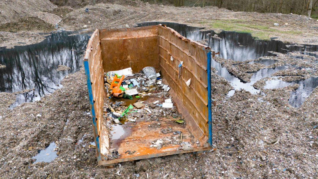 Waste container with some rubbish inside sitting on cleared land