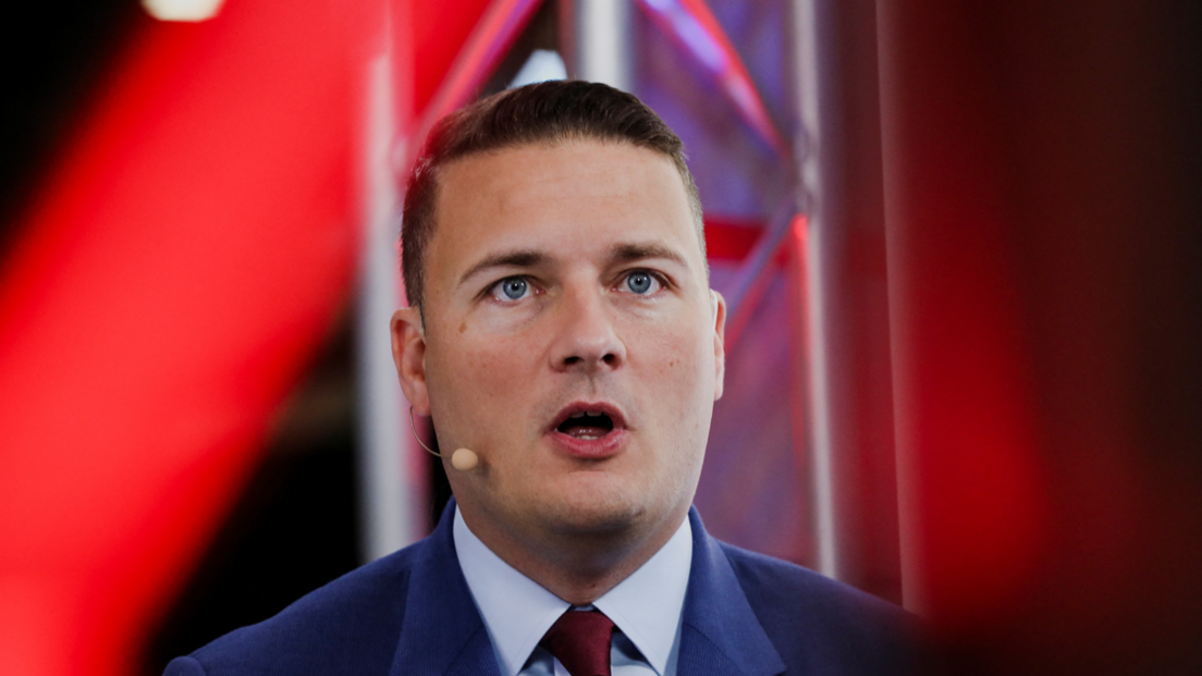 Health Secretary Wes Streeting addressing an audience with a small microphone, attached to his right ear, extending to his right cheek