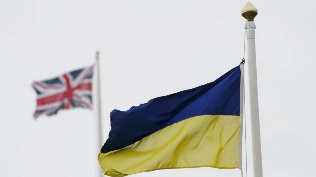 A Ukrainian flag with a UK flag behind it, flying on separate flag poles.