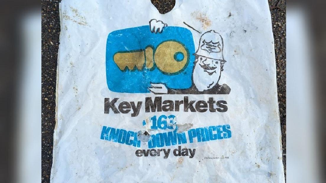 A white plastic carrier bag which states "Key Markets knock down prices every day" on it. There is an image of a police officer holding a key on the front of the bag. 