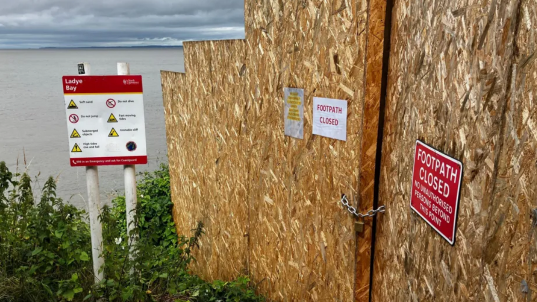 Warning signs and a temporary wall blocking the unstable clifftop walk and Ladye Bay