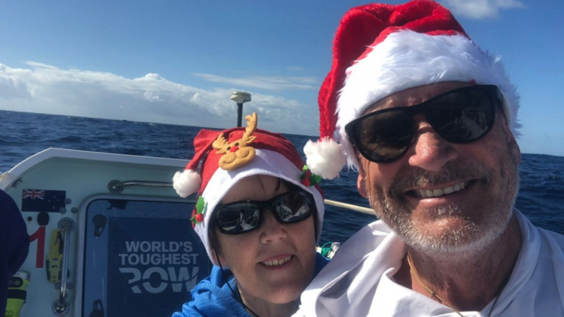 The couple are on their boat in the sunshine and are wearing Christmas hats