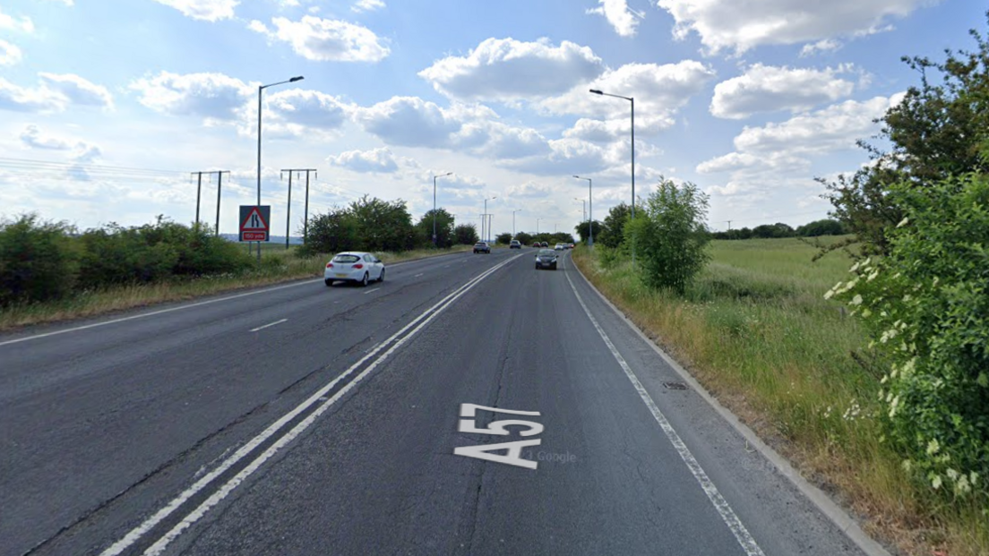 A Google maps image of the A57 heading west: a grey tarmac dual carriageway with green hedges on either side