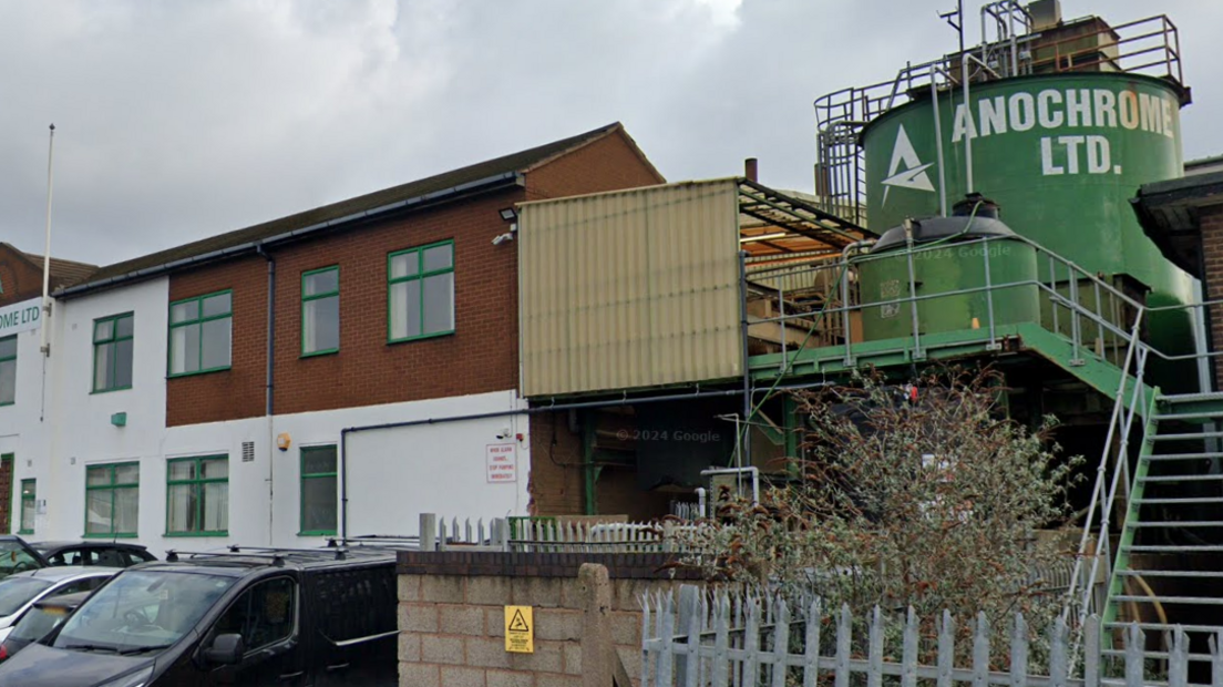 A two-storey white and brick building, with a large green storage tank to the right of the property, emblazoned with the words Anochrome Ltd