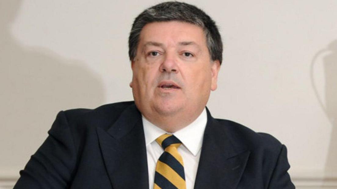 A man wearing a black blazer with a black and yellow tie.