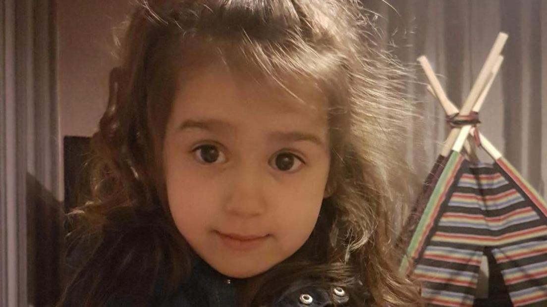 A handout image shows Sara Sharif, a 10-year-old girl whose father and stepmother have been convicted of her murder. At the time the image was taken, she was four. She had long brown hair and is seen looking into the camera. 