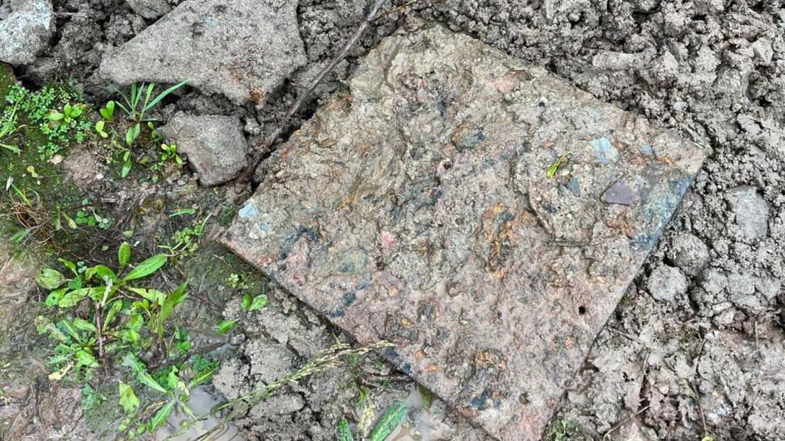 Large steel plate. The item is on the ground and is covered in mud an debris. 