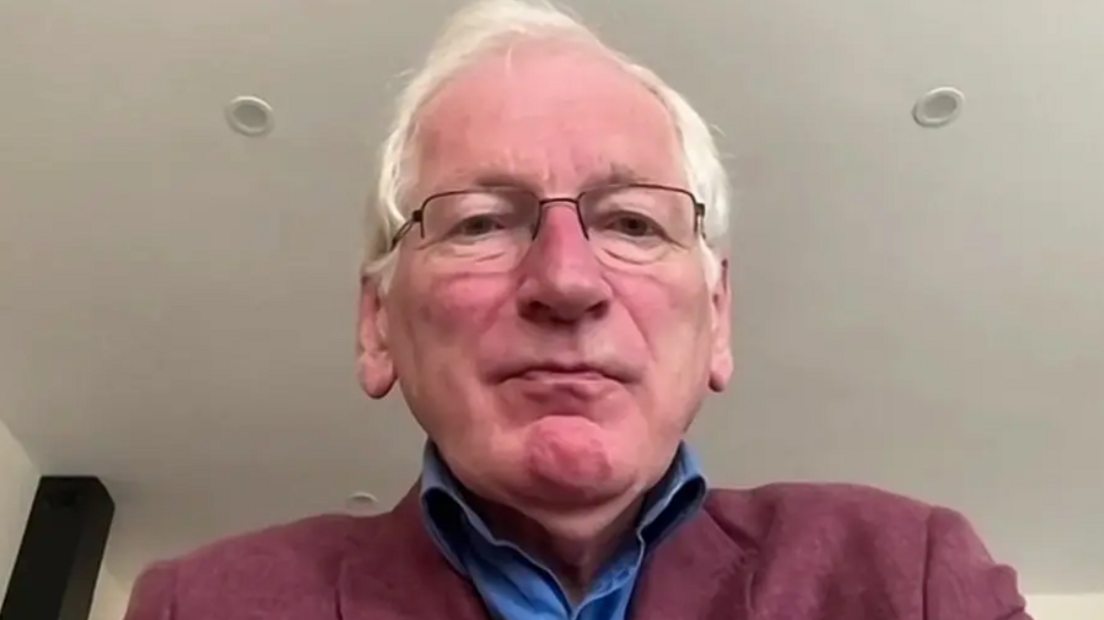 A Teams-call style head and shoulders image of white-haired Dr Dewi Evans, in a blue shirt and light purple jacket