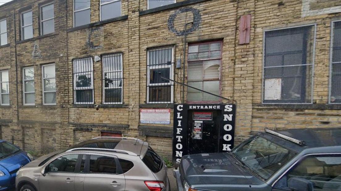 The entrance to a snooker hall, built into an old mill building, with barred windows.