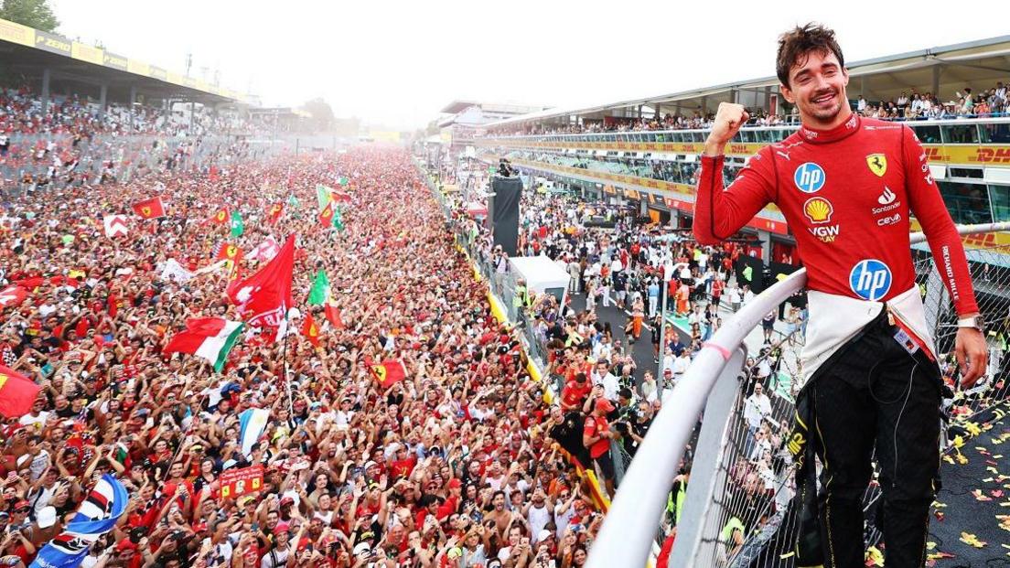 Charles Leclerc poses with Ferrari fans behind him