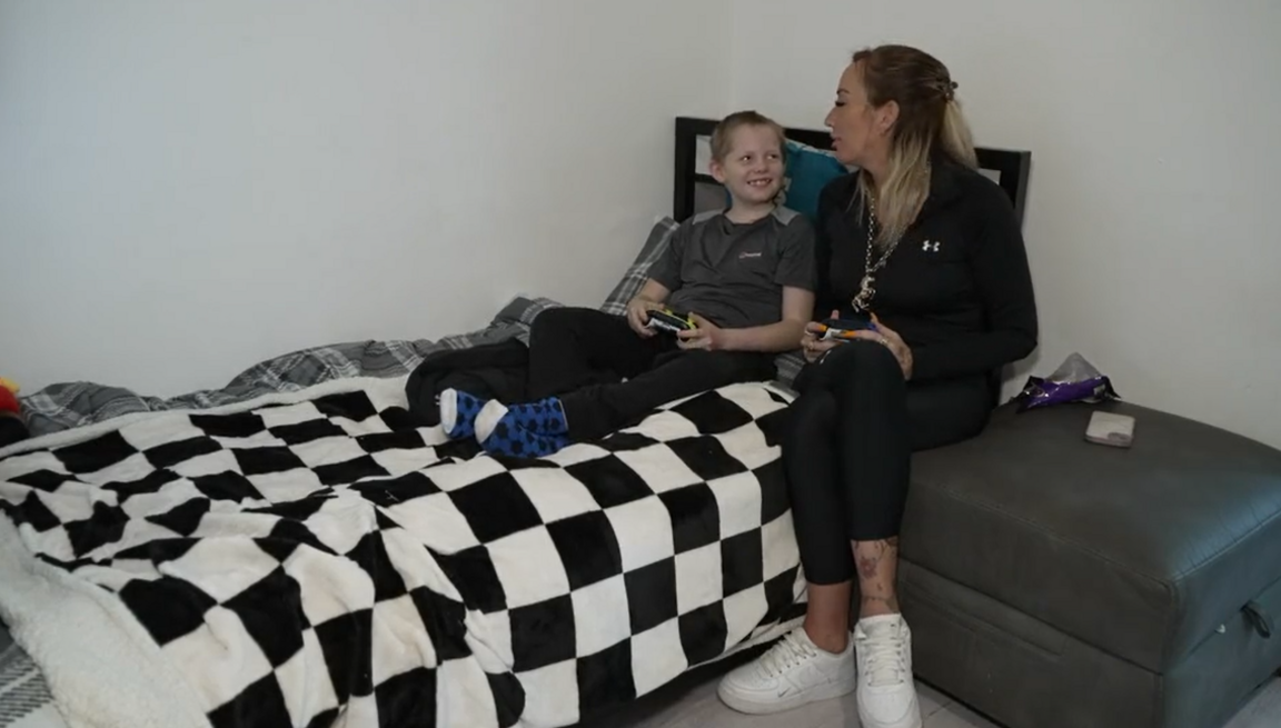 Boy in bed with mother sat beside him