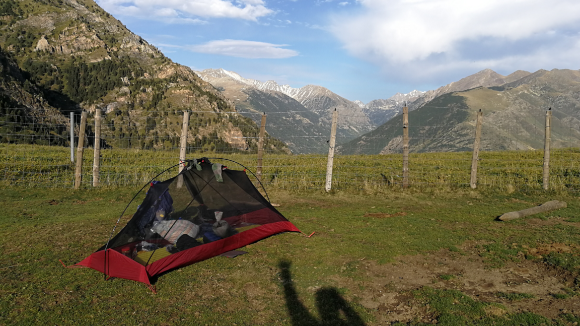 A red tent with black mesh set up in the Pyrenees mountain range
