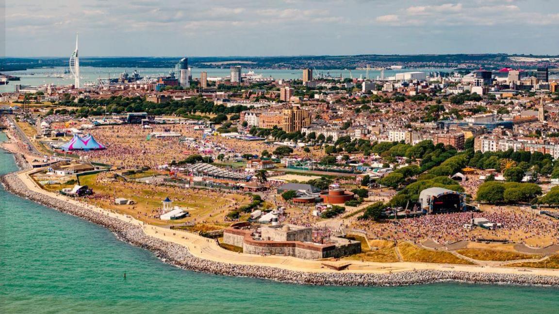 Aerial view of Victorious Festival along Southsea seafront - numerous music stages can be seen with the sea wall and sea running along the edge of the festival site.