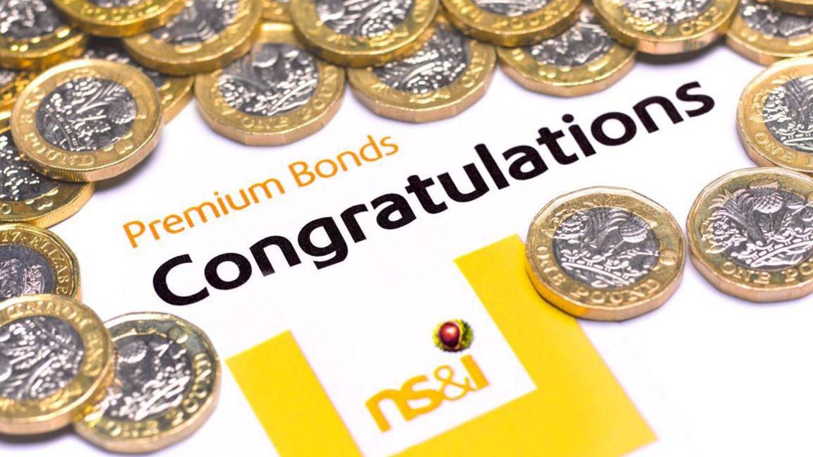 A pile of silver and gold coloured one pound coins arranged around words which read Premium Bonds, congratulations, NS&I