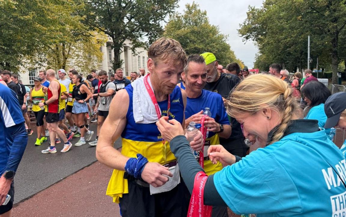 Runners queue up to have their medals put around their necks