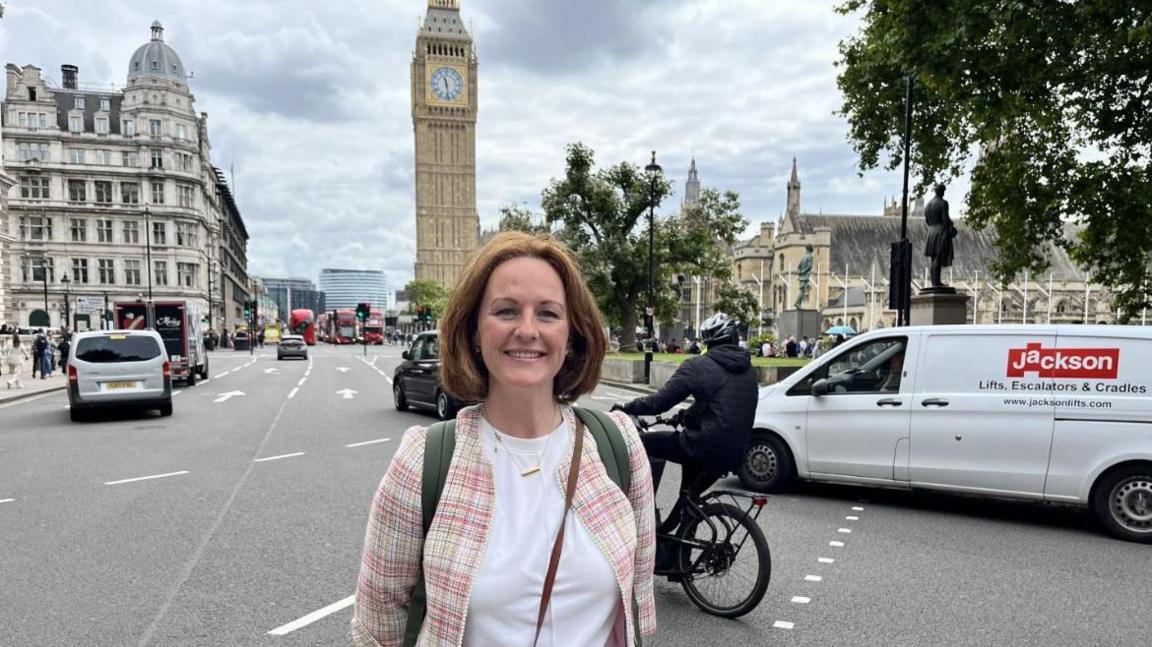 Ms McEvoy stands in front of the Elizabeth tower in London with busy traffic behind her