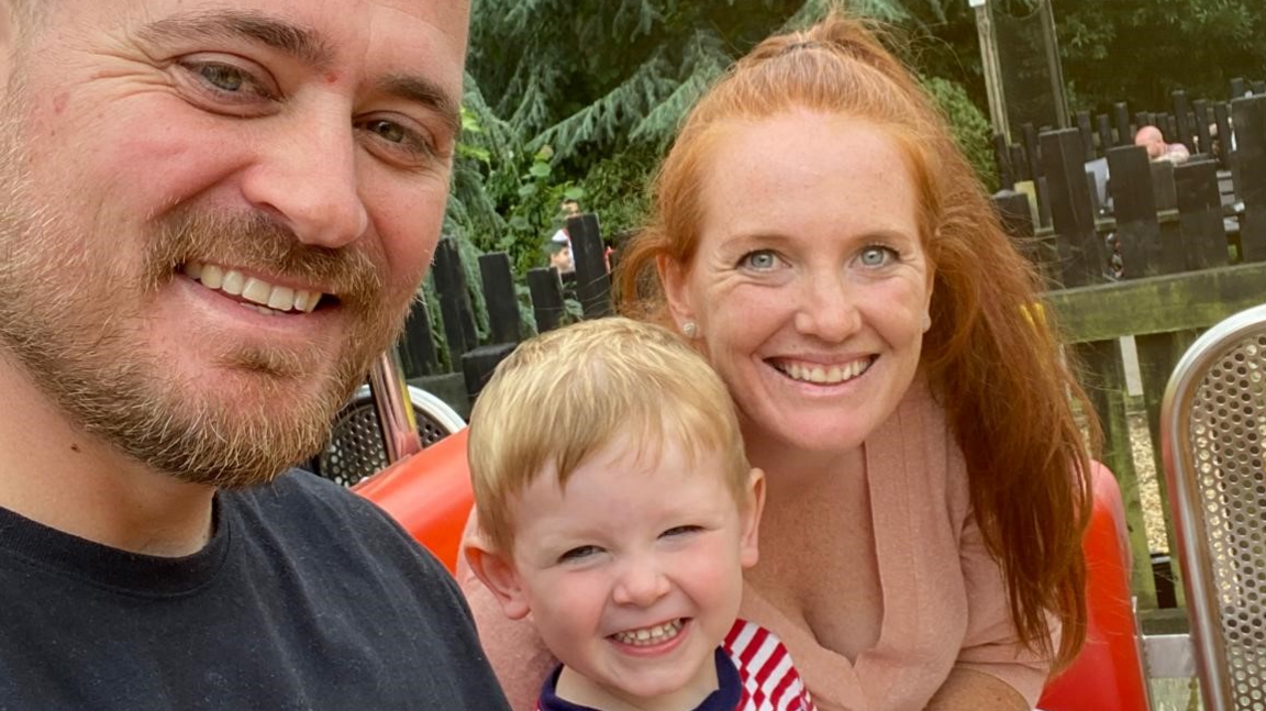 Ashley Bishop, with his wife and son, all smiling at the camera