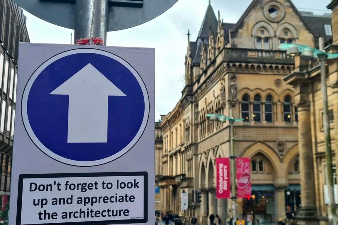 A photo of a building in the centre of Glasgow with a sign that says Don't forget to look up and appreciate the architecture