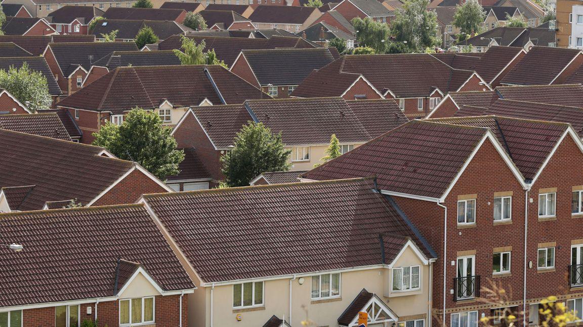 A view across the rooftops of a new-build housing estate, with properties of various sizes packed together.