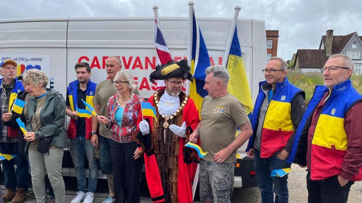 A team of people with Ukraine flags next to a white van