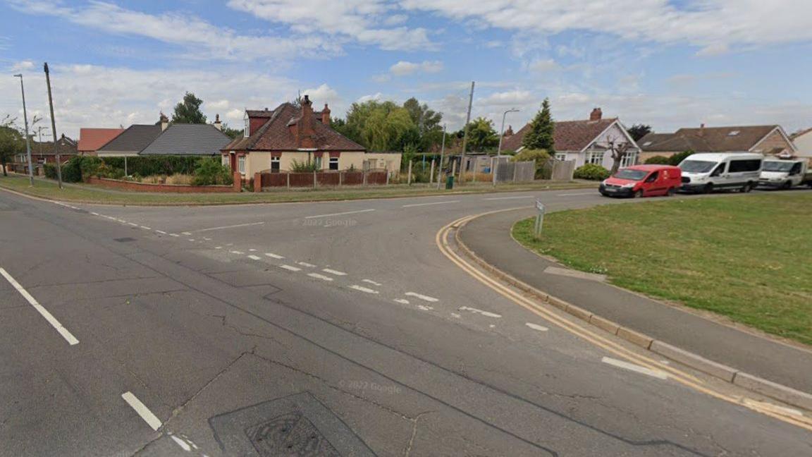 A damaged section of the A153 at the junction with Hemingby Lane in Horncastle. To the left is a patch of green land and in the background are bungalows and parked cars