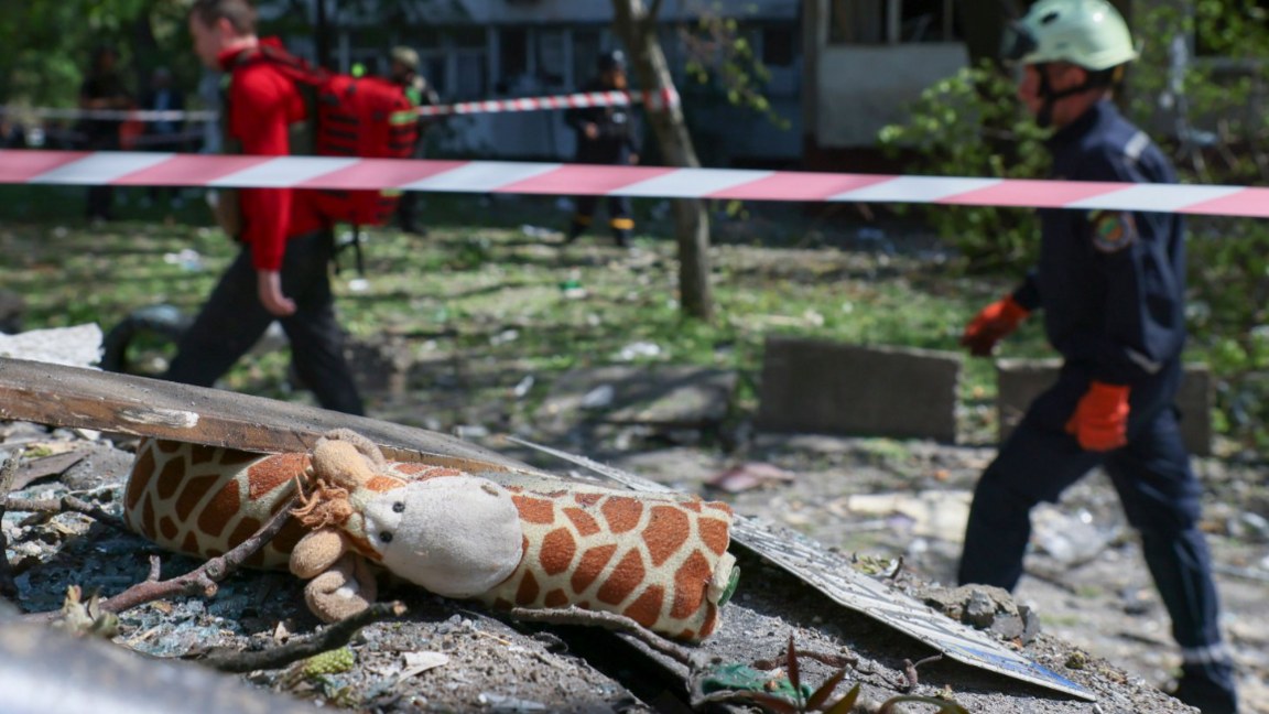 Ukrainian rescuers walk past a child's toy of a giraffe at the site of a damaged high-rise residential building after a Russian missile strike in Zaporizhzhia, southeastern Ukraine on 22 April 2025