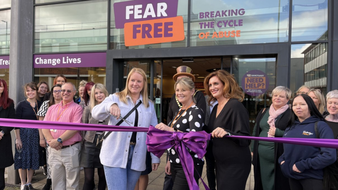 A group of people outside the Fear Free shop with one cutting a purple ribbon