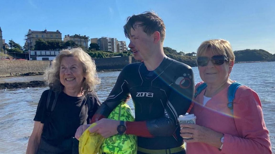 Harrison in a wetsuit with two women