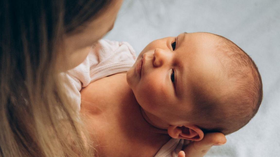 Mother holding a newborn baby and looking into the baby's eyes