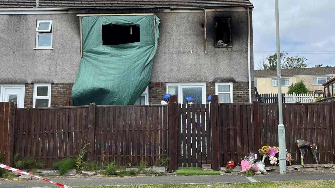 Floral tributes are seen outside the property in Swansea on Sunday