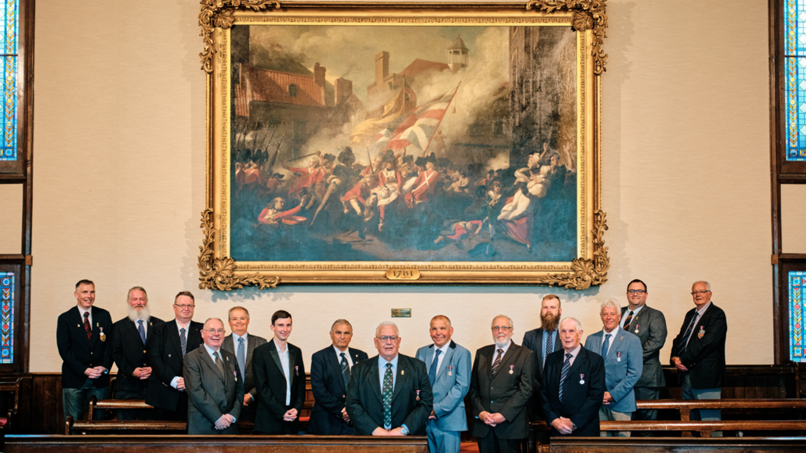 The 1781 Jersey Militia in front of the painting of the Battle of Jersey