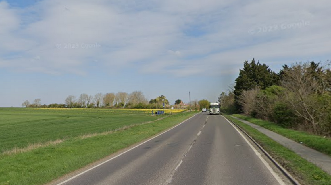 Google image of the A10 during the day. There is grass on either side of the road and a flat field.