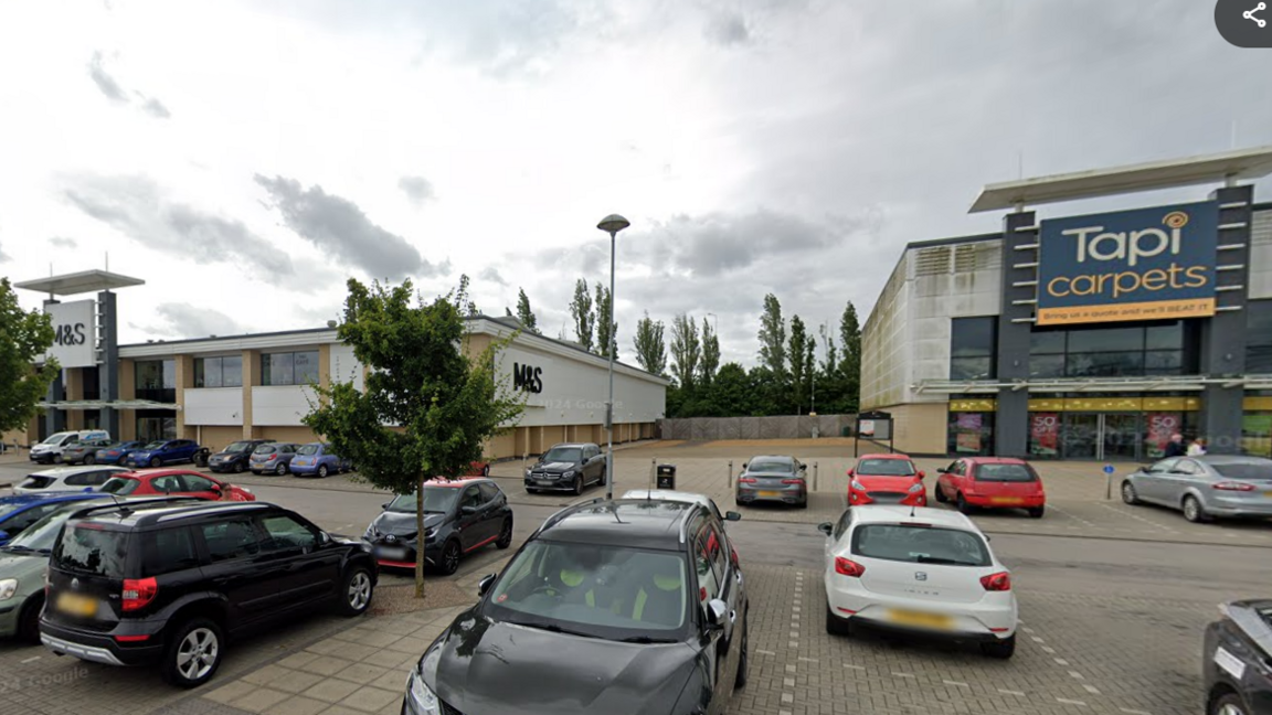 Car park view of M&S at Brotherhood Shopping Park and the empty space between in and Tapi. 
