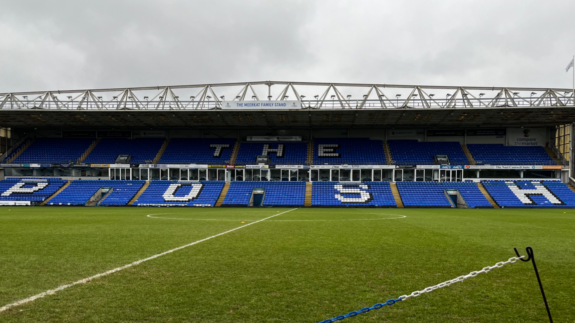 The football pitch is empty and the words 'The Posh' can be seen on the seats in the opposite stand.