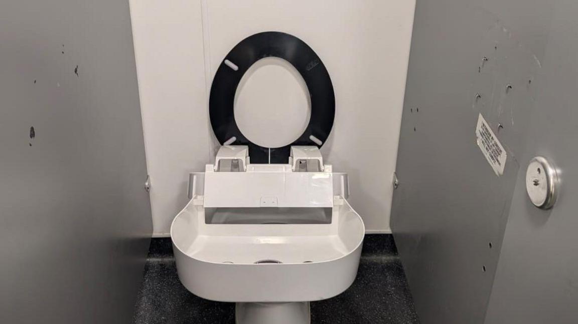 A toilet in a public facility is missing the seat