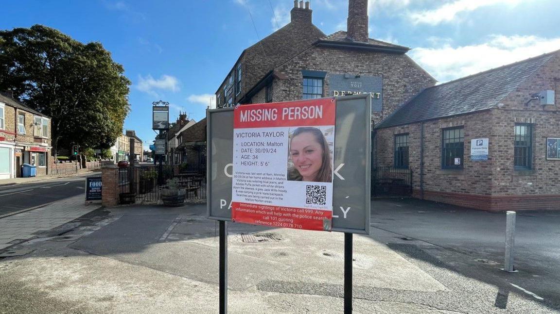 A picture showing a poster on a sign displaying an image of missing woman. 