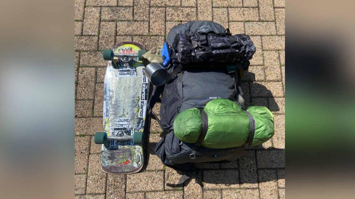 A large backpack and skateboard lie on the ground. 