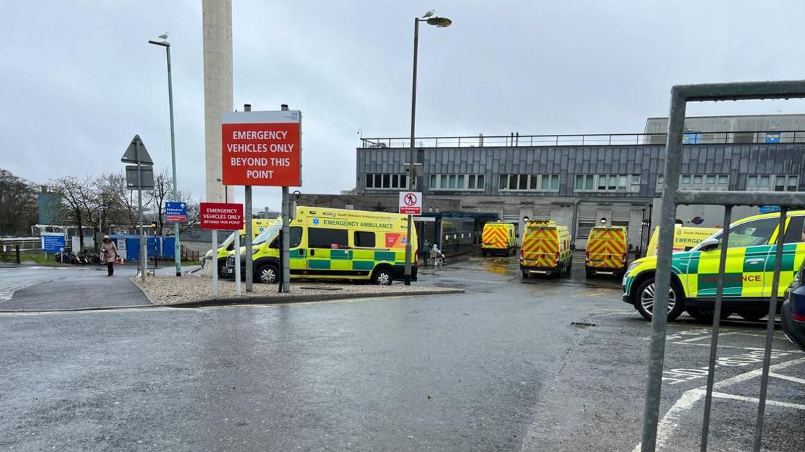 Ambulances parked outside Derriford Hospital in Plymouth on a rainy day.