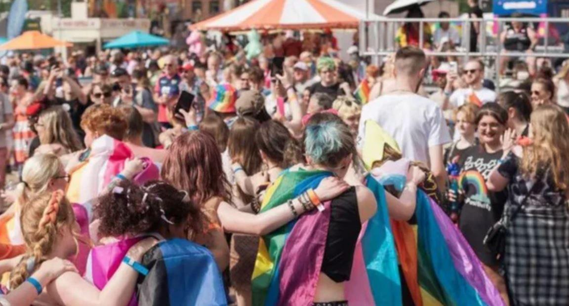 Crowds gather in the city for the party. Umbrellas can be seen along with flags draped on some revellers, some forming a "conga" line, enjoying themselves.