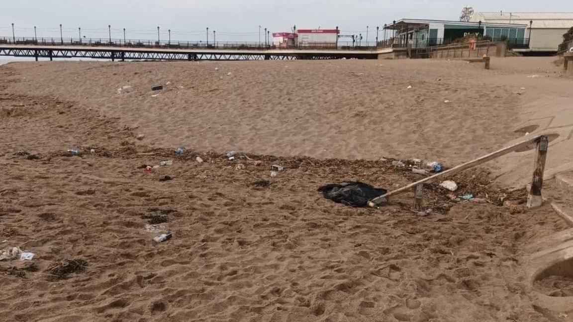 Skegness beach with the pier in the background, no one is on the beach but it is covered in litter