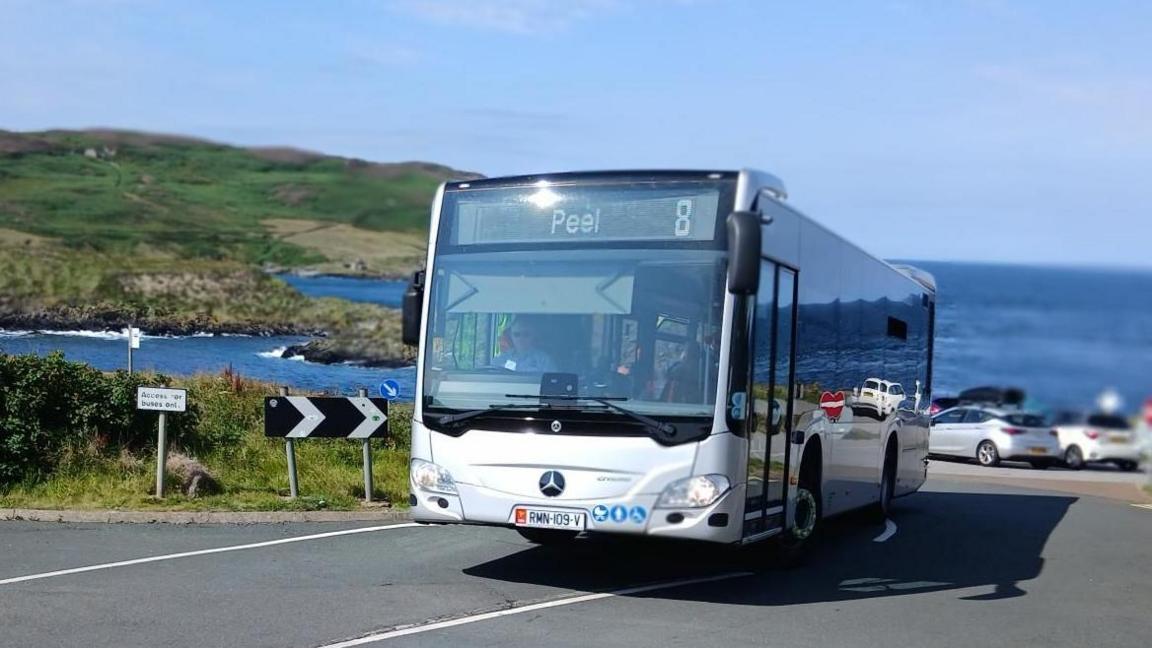 The new bus, it reads Peel 8 and is driving away from The Sound, you can see the Calf of Man, an island in the background.