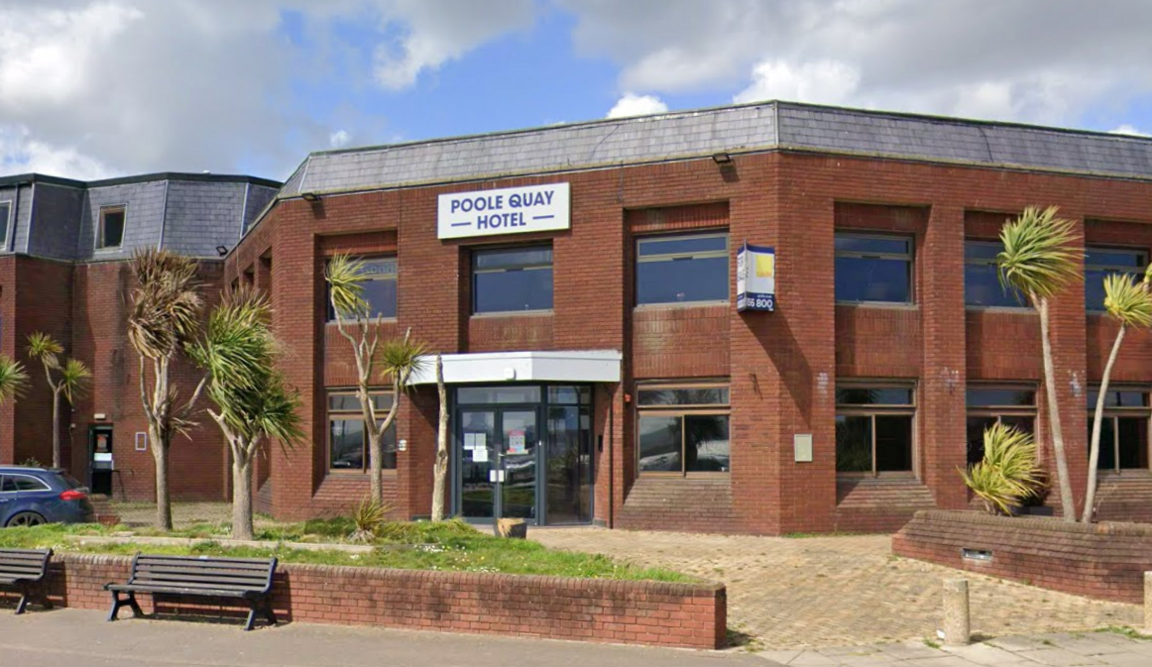 Google Street View of Poole Quay Hotel, a two-storey 1980s red brick building with a patch of grass and a low brick wall separating it from the pavement