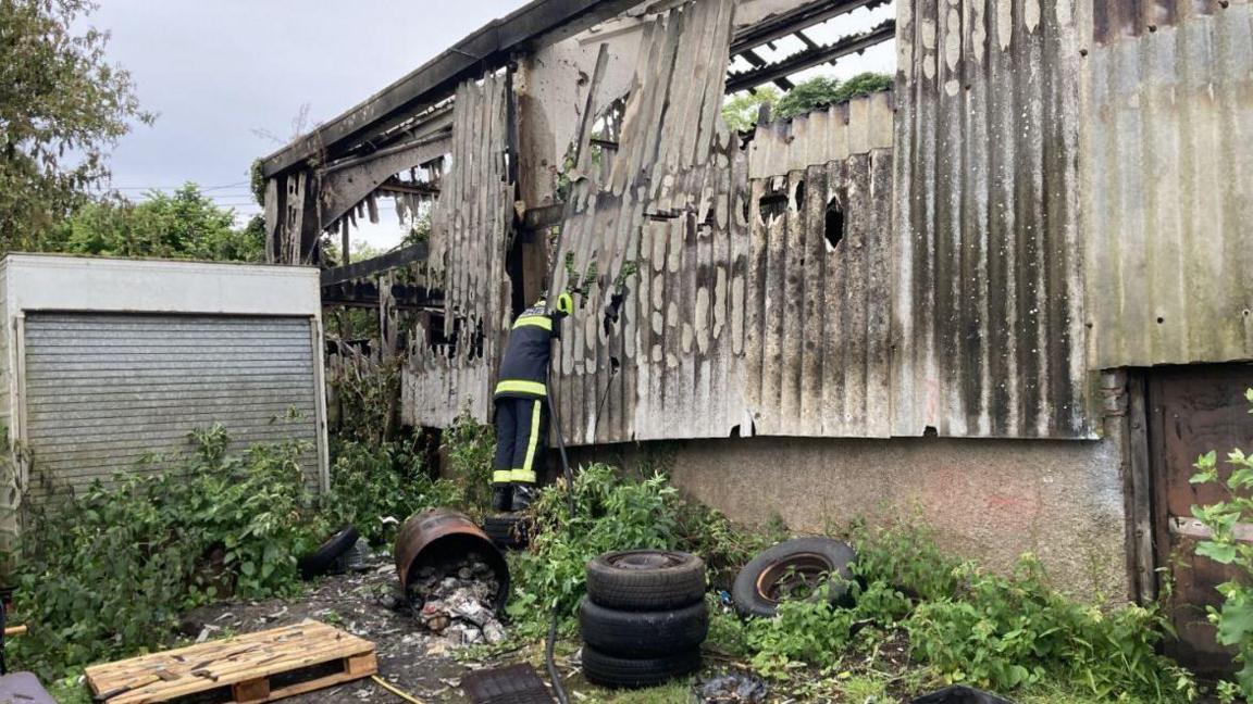 Workshop fire near Poltimore, a fire fighter is examining the damage