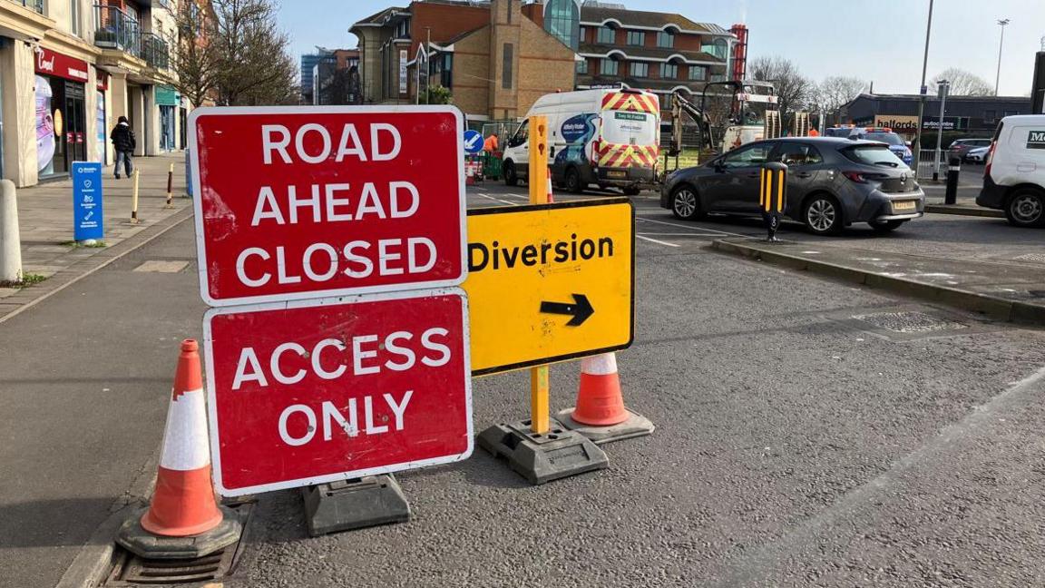 Red street sign saying road closed ahead and access only