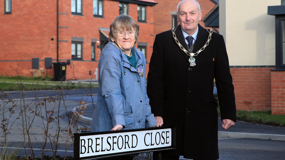 Mrs Susan Brelsford stood with Councillor Robert Bullock at a street sign reading Brelsford Close.