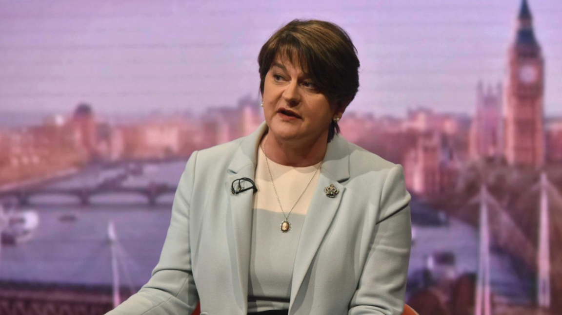 Arlene Foster, a woman with dark hair in grey suit. She is wearing a silver necklace.