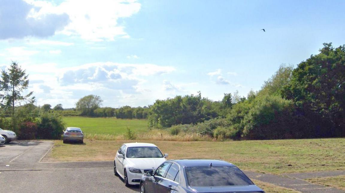 A selection of cars on a hardstanding area in front of green fields
