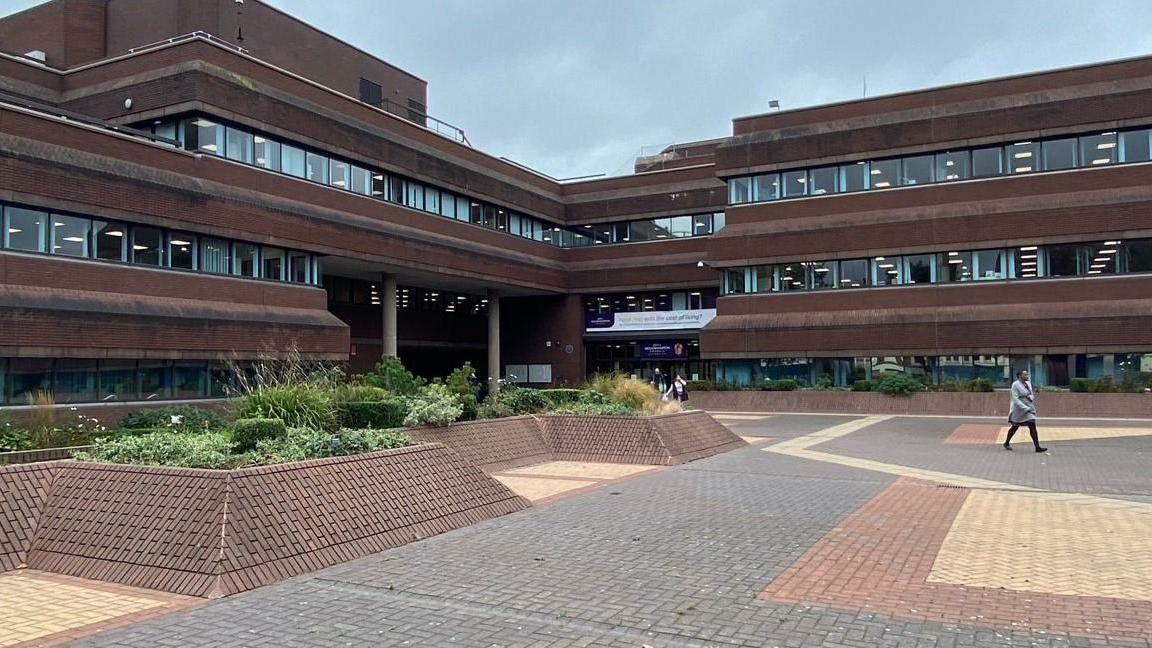 A person on the right of the shot walks across the courtyard outside the front of the Civic Centre in Wolverhampton.