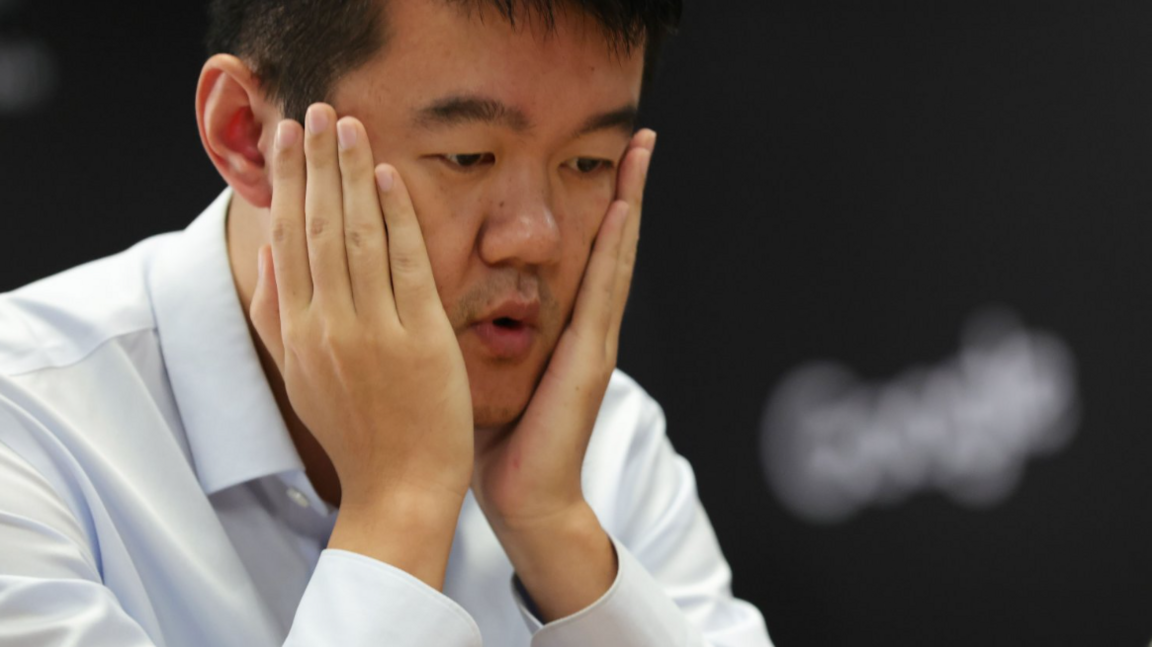 Ding Liren holds his hands to his face after realising his crucial mistake during the final game of the 2024 World Chess Championship. He is wearing a white shirt